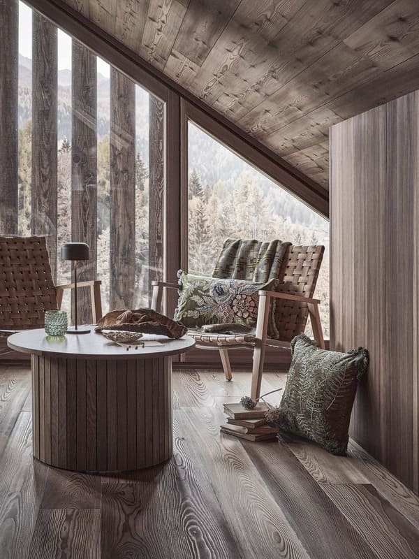 Angolo living della collezione Coincasa Abitare la natura con poltrone intrecciate, cuscini ricamati e plaid