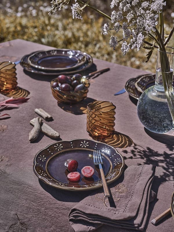 Tavola della collezione Coincasa Abitare la natura con piatti in ceramica bruna e bicchieri color ambra