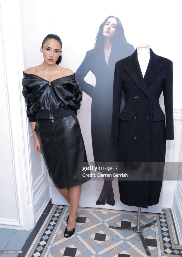 Cora Corré accanto a un cappotto nero della capsule collection con Marella, esposto durante il party di lancio a Londra