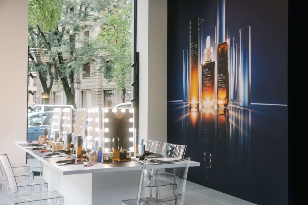 Postazione con specchi luminosi allestita nel pop-up Estée Lauder "Written in the Stars", con il visual della linea Advanced Night Repair sullo sfondo