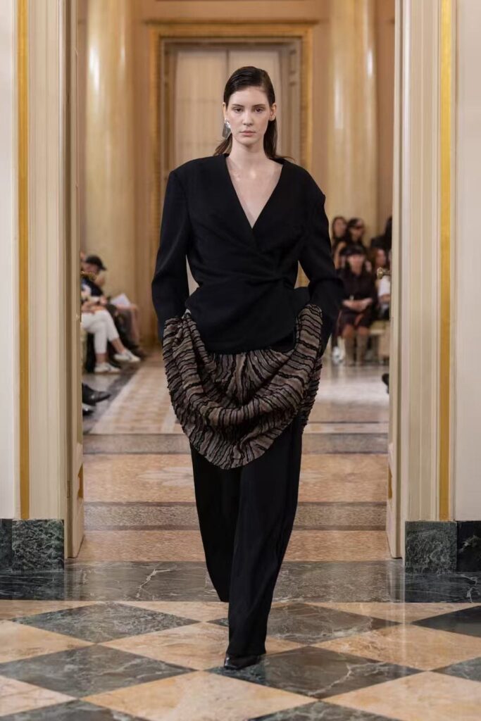 Look nero Liu Hongchao con scollo a V, pantaloni ampi e un drappeggio a righe irregolari sui fianchi.