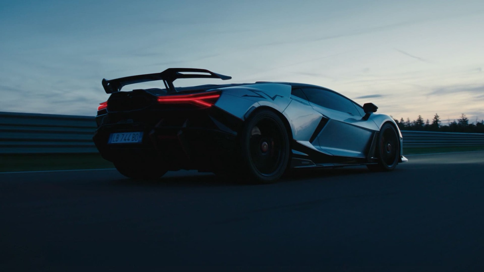 La Lamborghini Revuelto Super Veloce ripresa da dietro su un circuito al tramonto, protagonista del film "The Quantum of Driving"