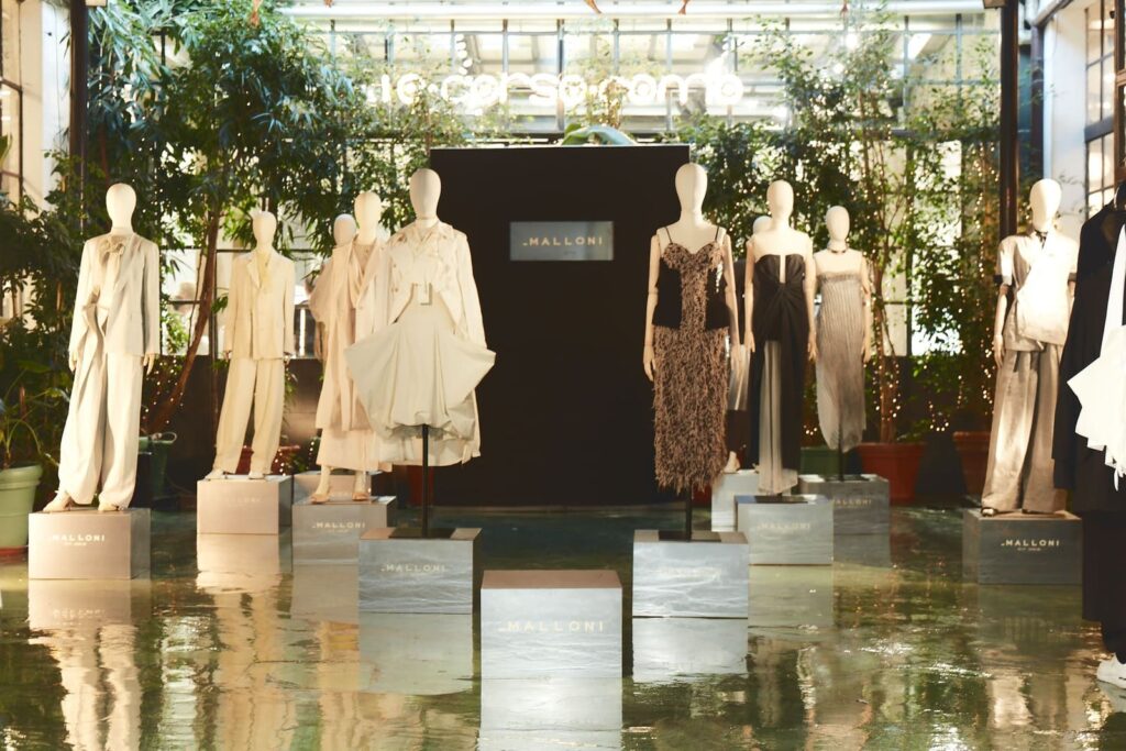 Manichini con completi chiari e abiti scuri della collezione Malloni primavera-estate 2027 su podi a 10 Corso Como.