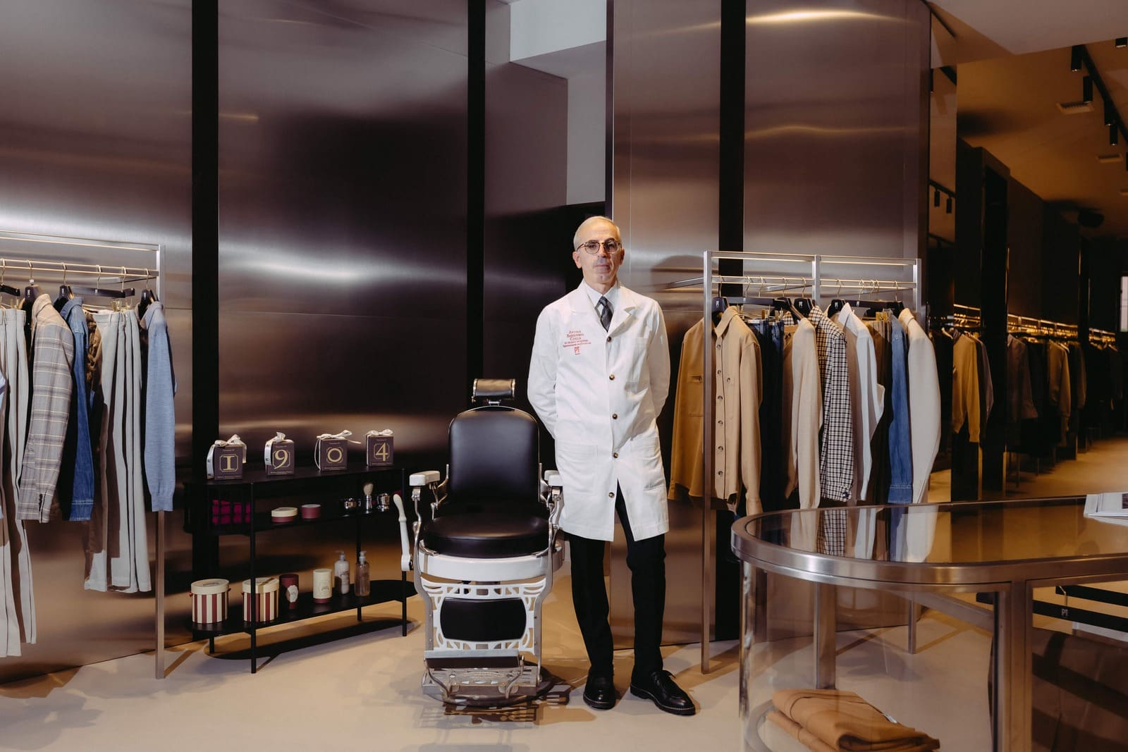 Maurizio Prota nella boutique PT Torino di Milano, accanto a una poltrona da barbiere e alle Colonie 1904 di Antica Barbieria Colla.
