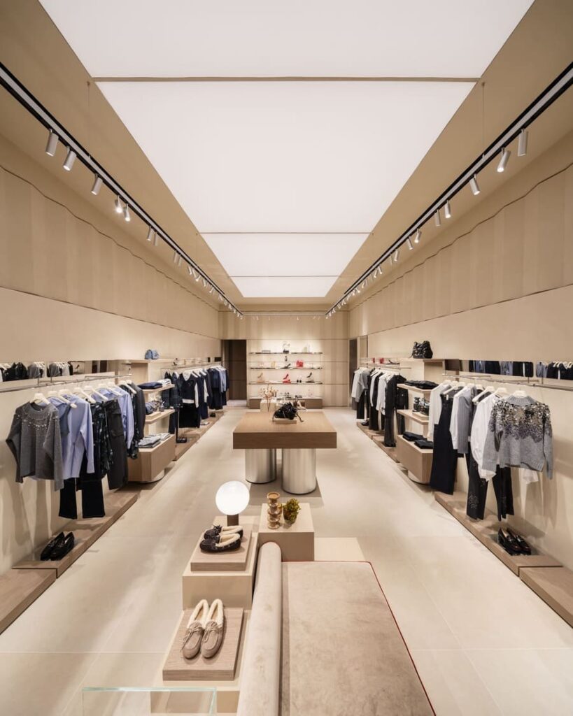 Sala del negozio Liu Jo con abiti lungo le pareti, tavoli per gli accessori e una seduta al centro.