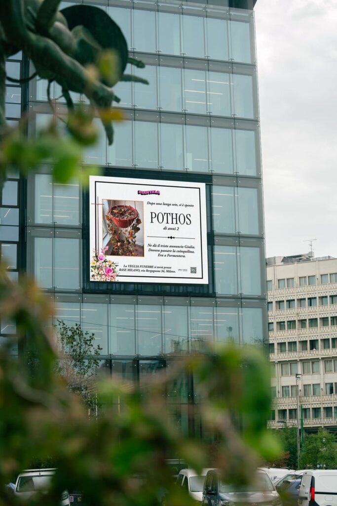 Necrologio urbano dedicato alla pianta Pothos su un maxischermo di Milano, campagna DOOH di Piantala in media partnership con Urban Vision Group