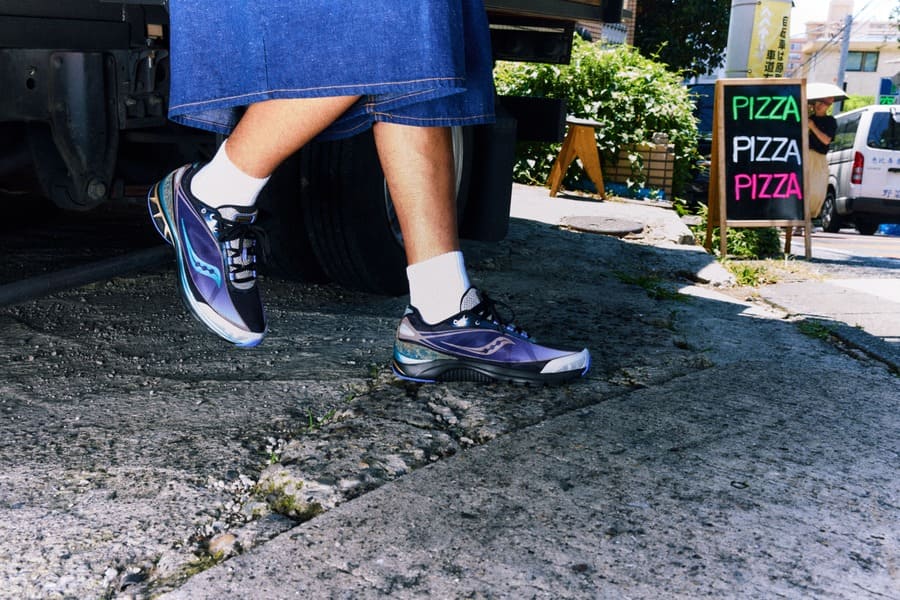 Sneakers Saucony Daikanyama nei toni del viola, con dettagli turchesi, indossate in strada con shorts in denim e calze bianche.