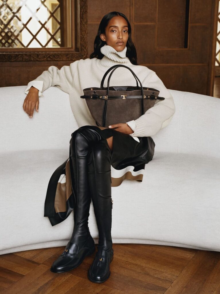 Modella con la Tod's T Signature Bag in suede grigio e stivali cuissardes, campagna Italian Stories autunno inverno 2026-27