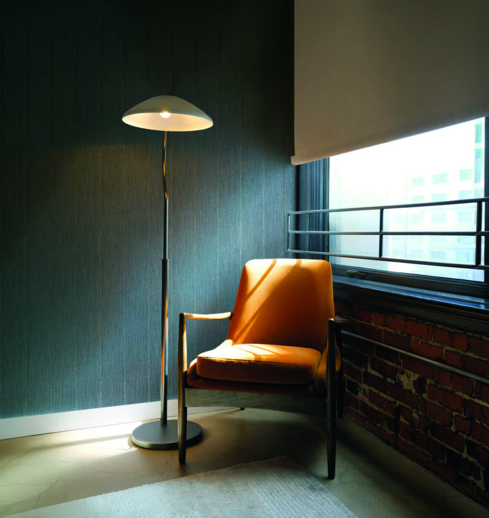 Rivestimento murale Regular della collezione AltaGamma Twill di Jannelli&Volpi in un angolo living con poltrona arancione e lampada da terra
