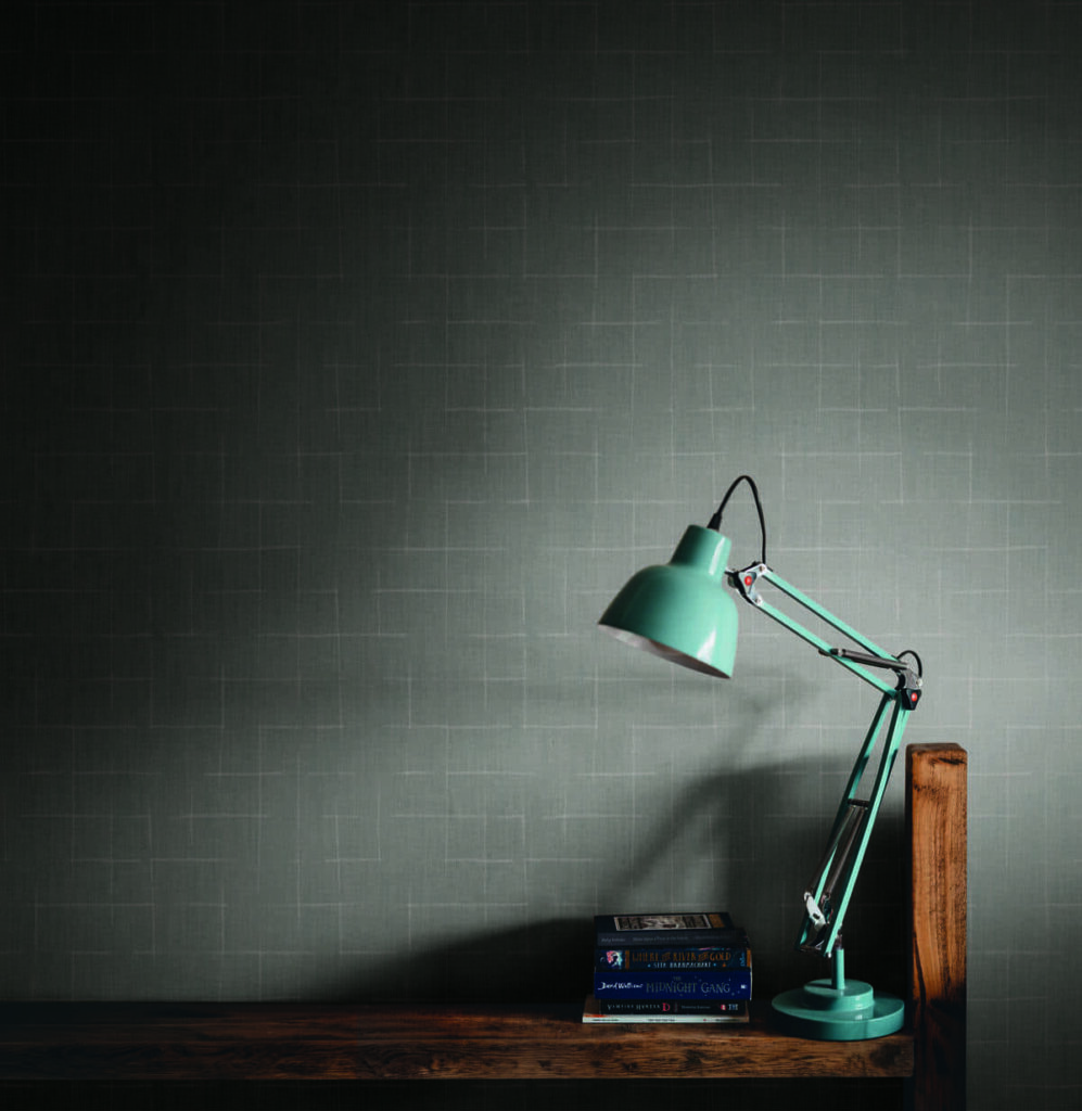 Rivestimento murale Wide della collezione AltaGamma Twill di Jannelli&Volpi con lampada da tavolo e libri impilati