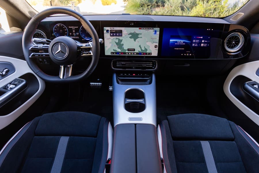 Plancia della Mercedes CLA Shooting Brake con volante, tre schermi e console centrale.