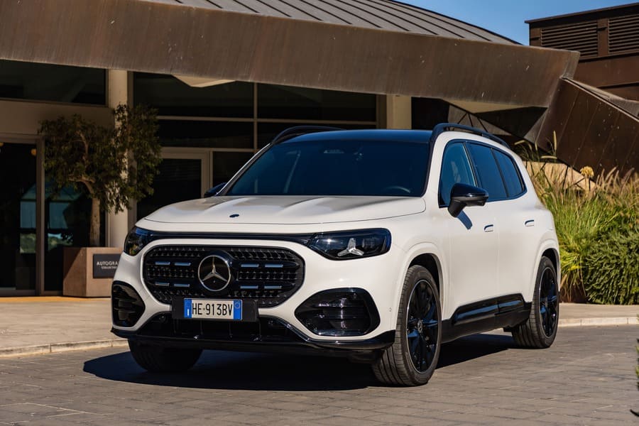 Mercedes GLB bianca con tetto scuro vista di tre quarti anteriore davanti a un edificio.